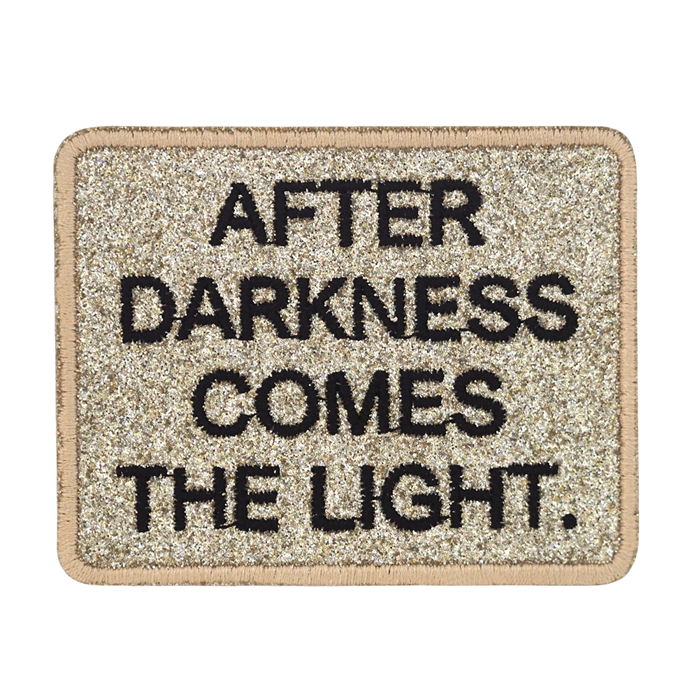 Brodeerattu kangasmerkki, teksti: After darkness comes the light.