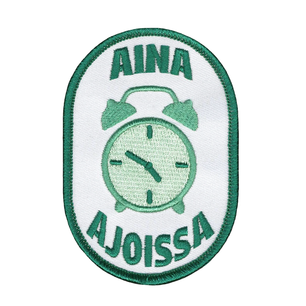 Brodeerattu haalarimerkki, kello, teksti: Aina ajoissa.