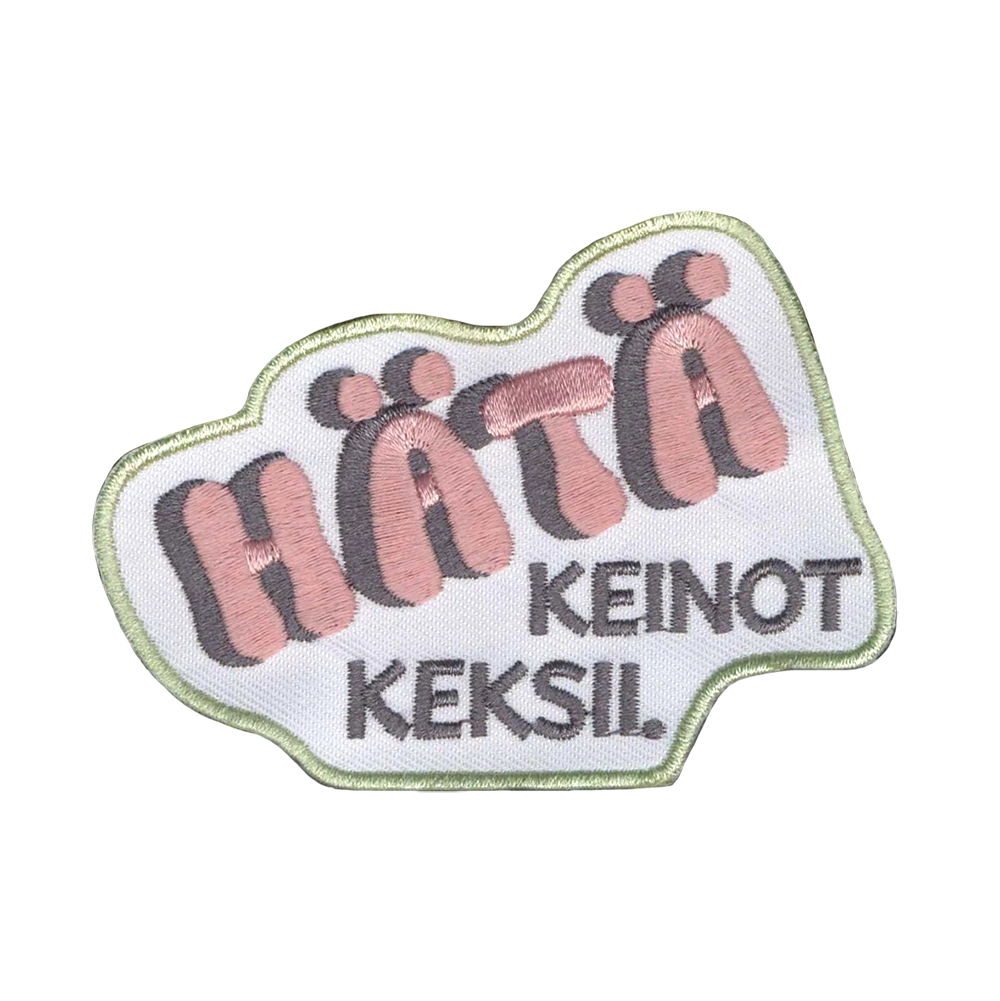 Brodeerattu kangasmerkki, teksti: Hätä keinot keksii.