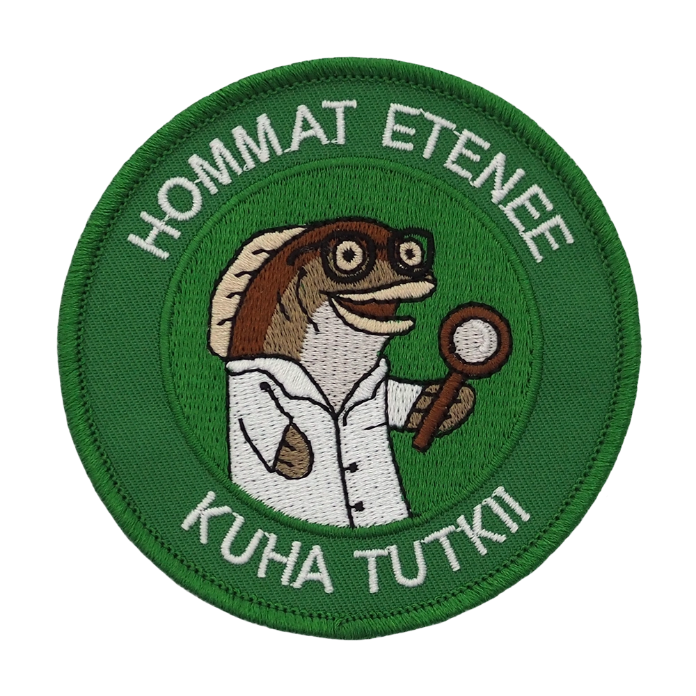 Brodeerattu kangasmerkki, teksti: Hommat etenee, kuha tutkii.