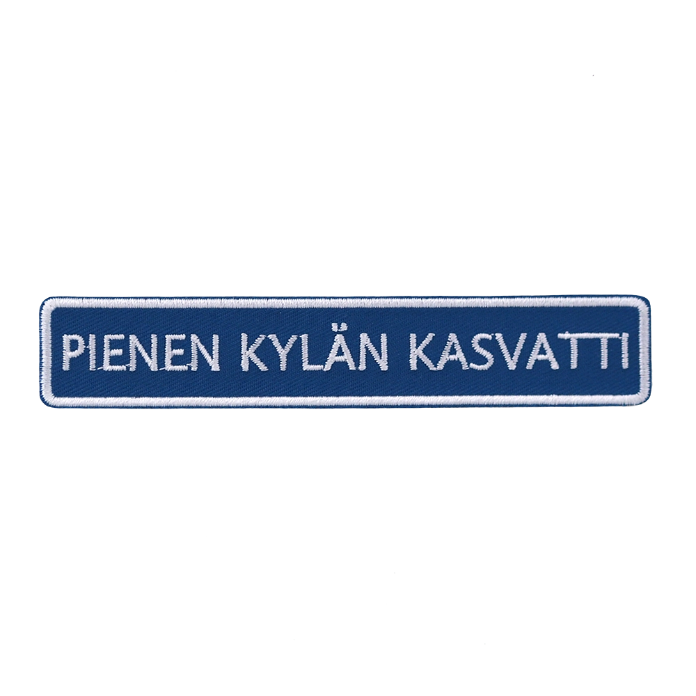Brodeerattu haalarimerkki, tiekyltti, teksti: Pienen kylän kasvatti.