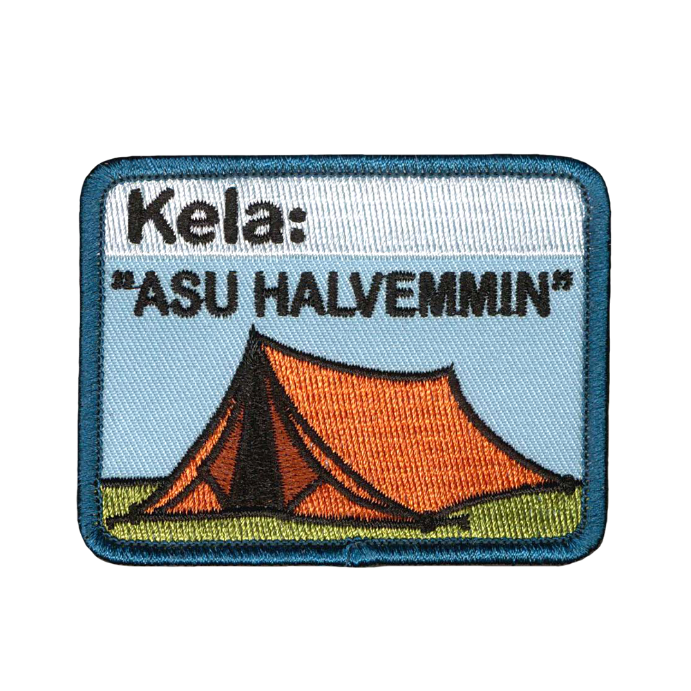 Brodeerattu kangasmerkki, teltta, teksti: Kela: Asu halvemmin. 