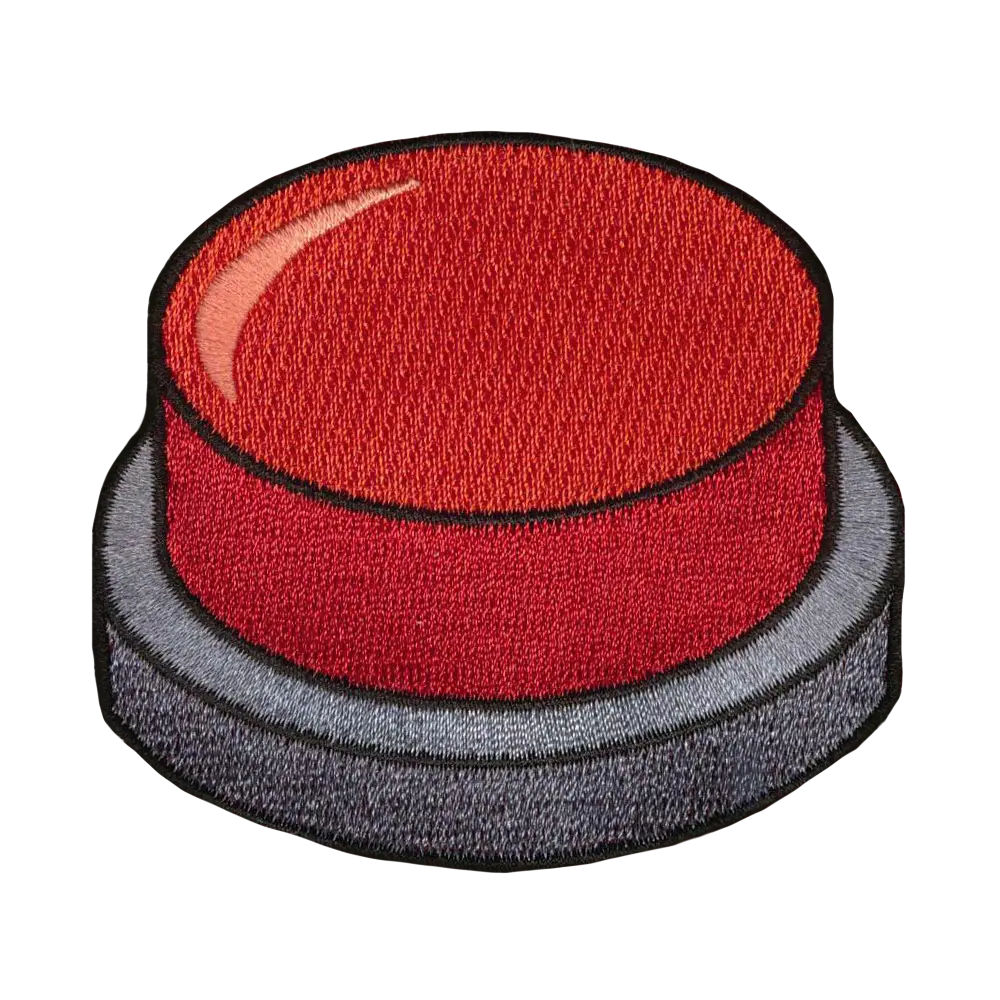 Brodeerattu kangasmerkki, paniikkinappula.